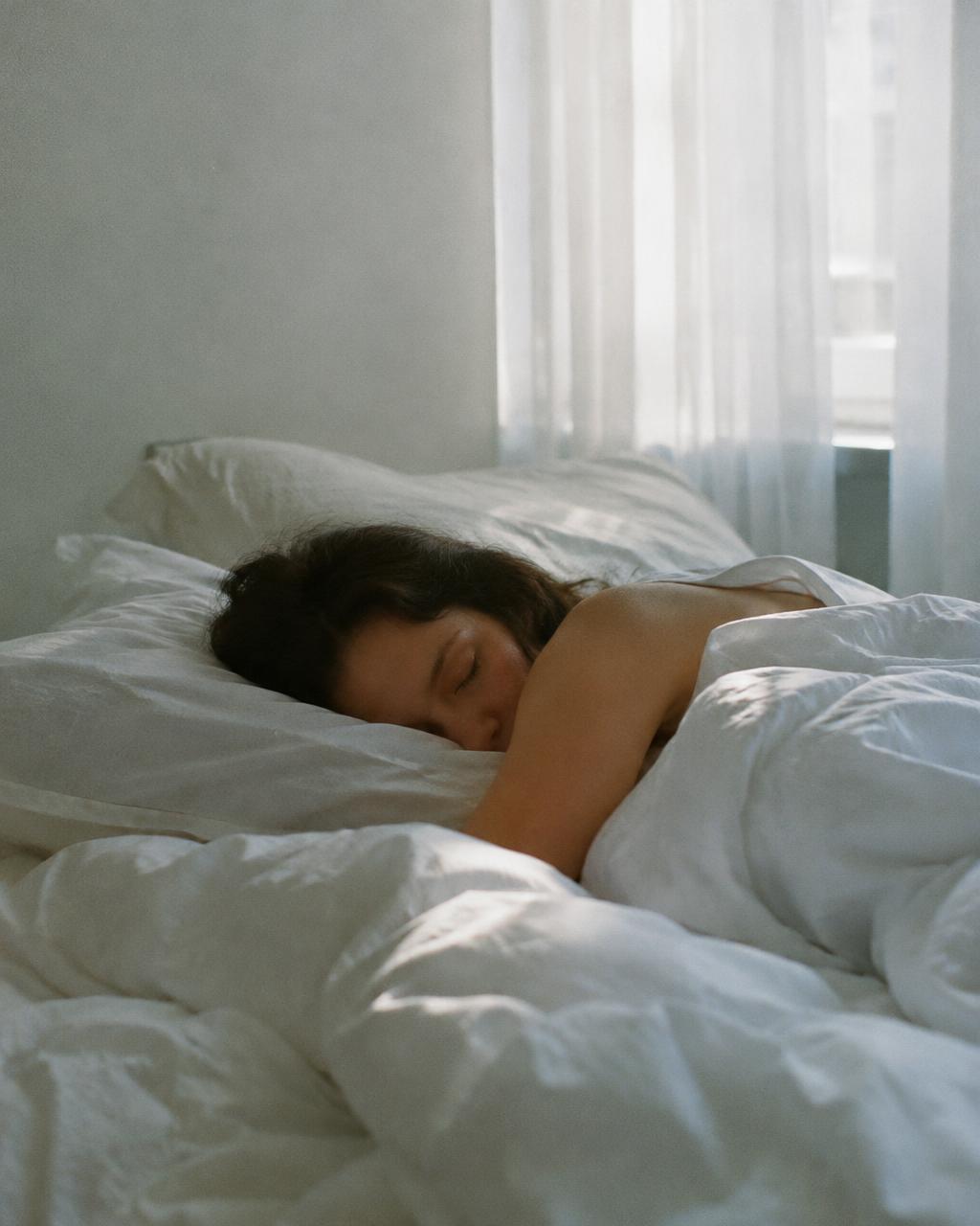 Persona durmiendo plácidamente en una cama con sábanas blancas